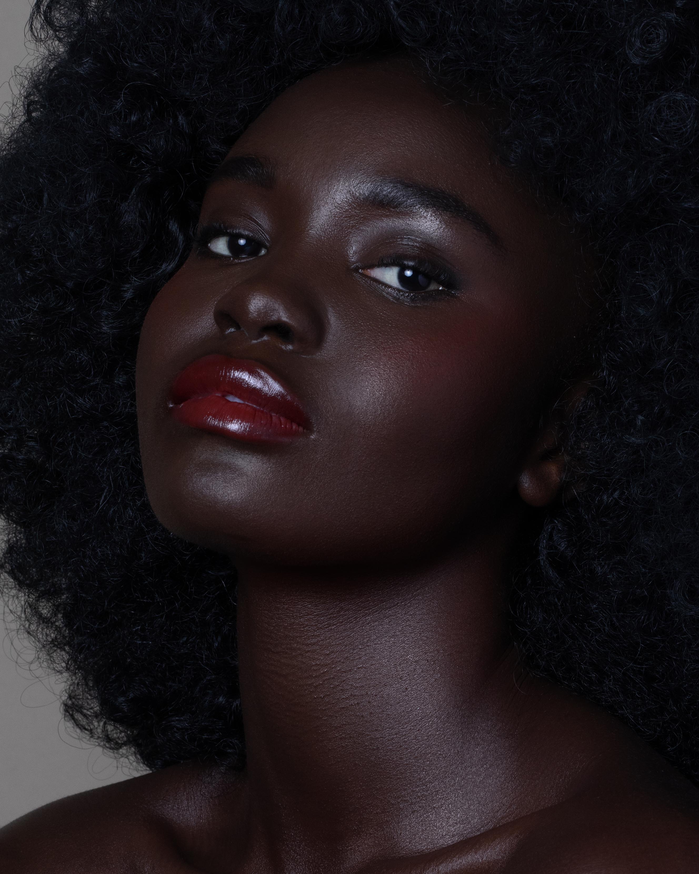 Close-up of a model with deep skin wearing red lip and cheek makeup